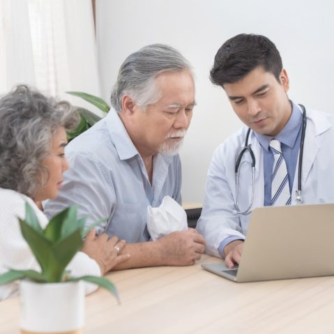 Caucasian doctor use laptop and talk with old asian male patient about disease symptom, elderly health check up at home.